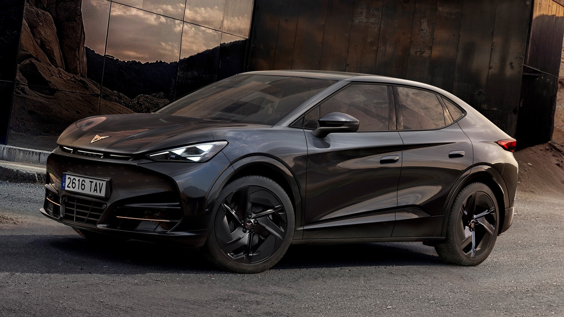 CUPRA Tavascan gris oscuro con rines multirradio negros frente a una estructura moderna