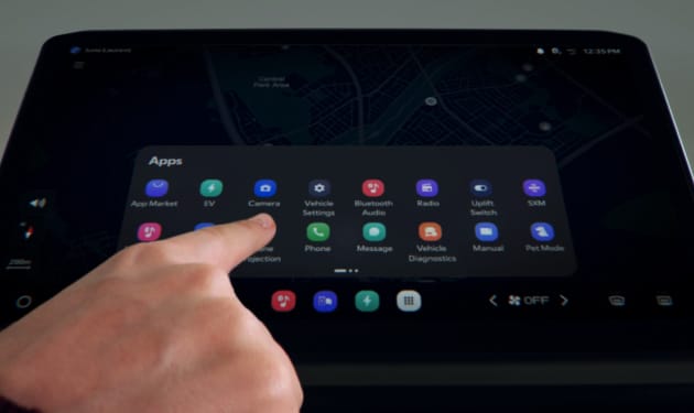 Pantalla de infoentretenimiento mostrando un menú de aplicaciones sobre un mapa, con un dedo tocando un icono.