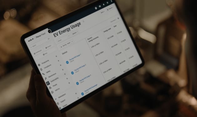 Persona sosteniendo una tablet con la aplicación Kia Fleet mostrando información de uso de energía de vehículos eléctricos de la gama PV5.