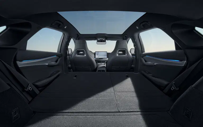 Maletero del SUV con los asientos traseros abatidos formando una superficie de carga plana, con techo panorámico y paisaje de lago al fondo