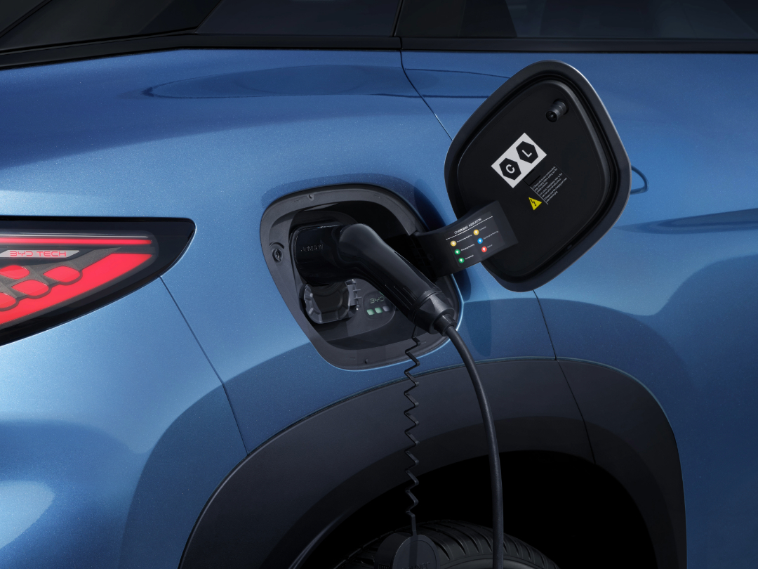 Primer plano del puerto de carga abierto del SUV plateado con el conector de carga rápida enchufado