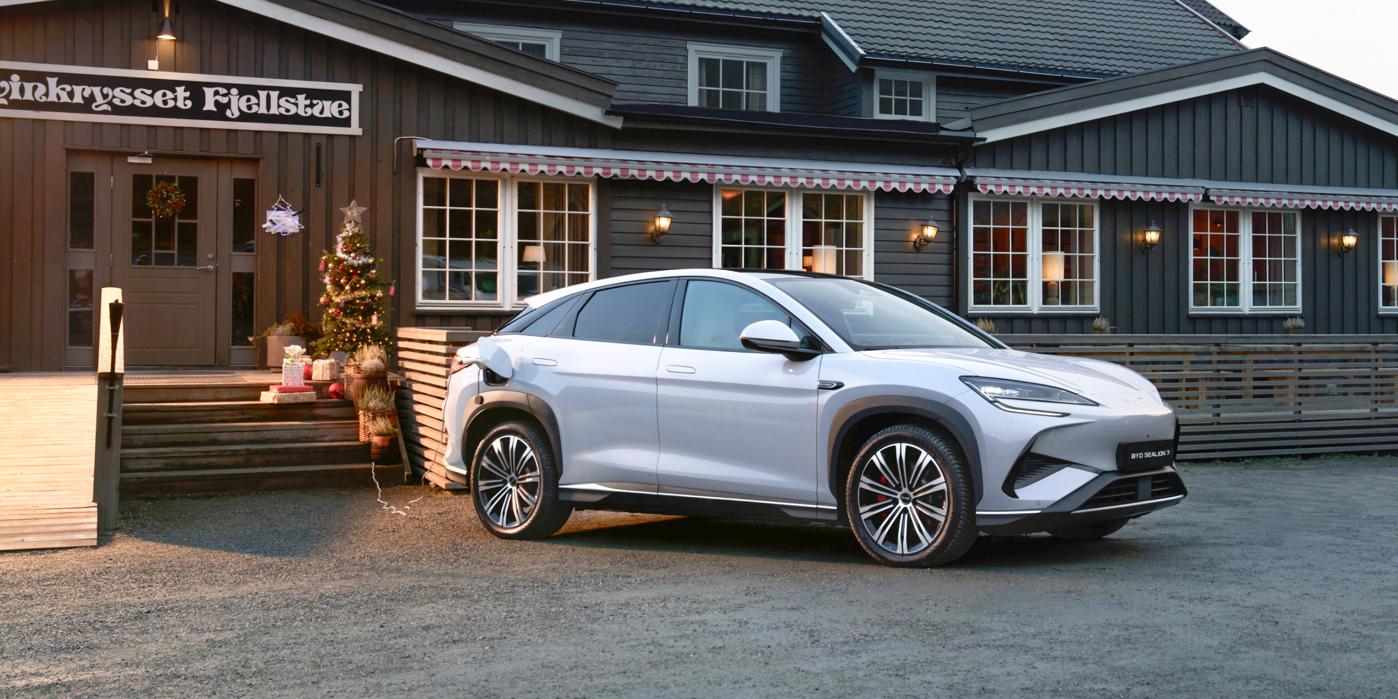 Adaptador V2L conectado al puerto de carga del SUV plateado alimentando un pequeño aparato de cámping