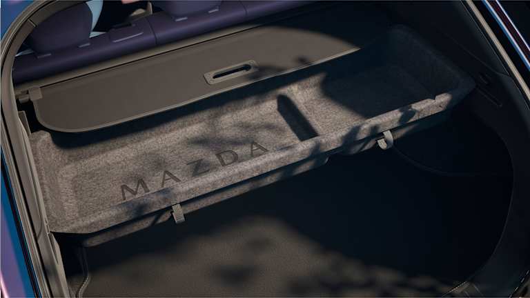 Maletero del Mazda CX-6e con la cubierta de carga con el logotipo MAZDA grabado.