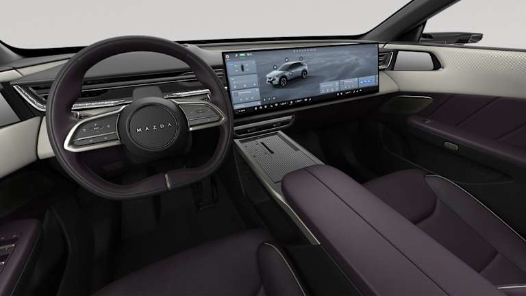 Volante con logo Mazda y doble pantalla de infoentretenimiento en un interior con acentos morados oscuros y crema.