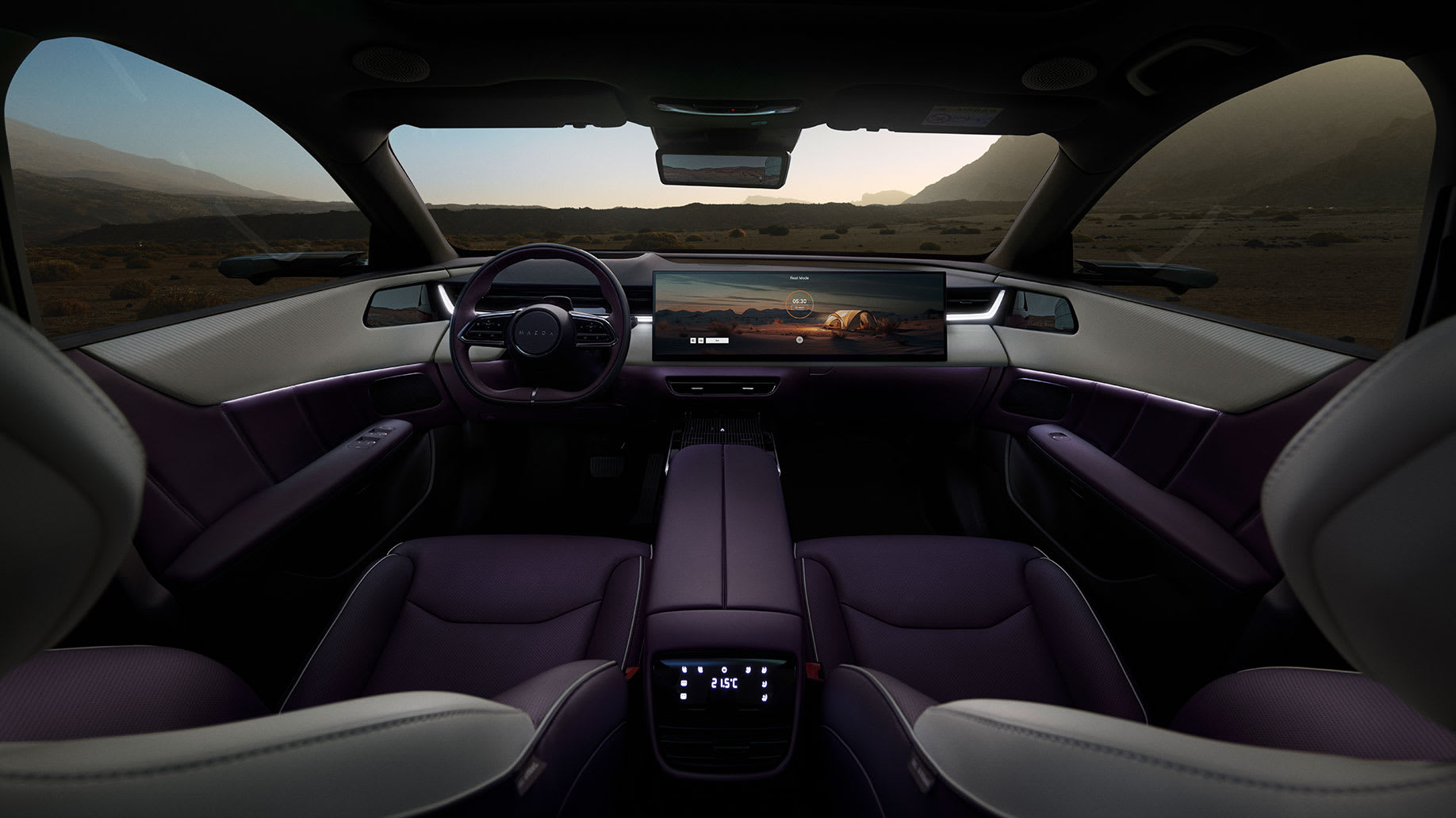 Interior del CX-6e con el volante con logo Mazda, gran pantalla central de infoentretenimiento y consola central en tonos oscuros.