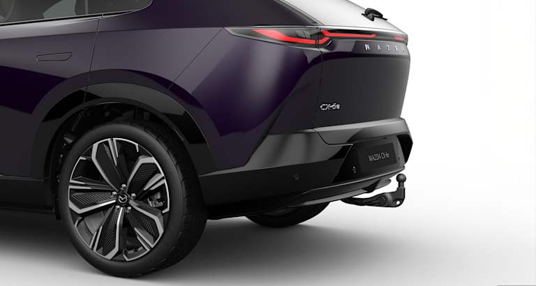 Mazda CX-6e púrpura oscuro en vista trasera tres cuartos con llantas multirradio.