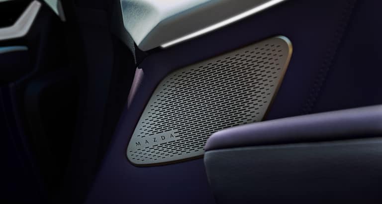 Panel de puerta con rejilla de altavoz Mazda y tira de iluminación ambiental en tonos oscuros.