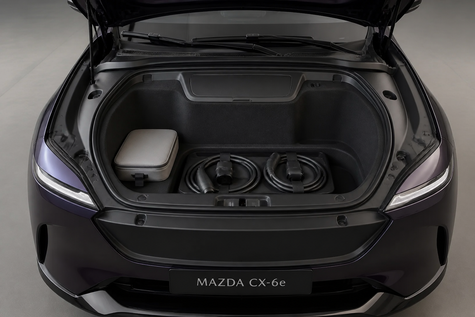 Maletero delantero del CX-6e abierto bajo el capó con los cables de carga ordenados en su interior.