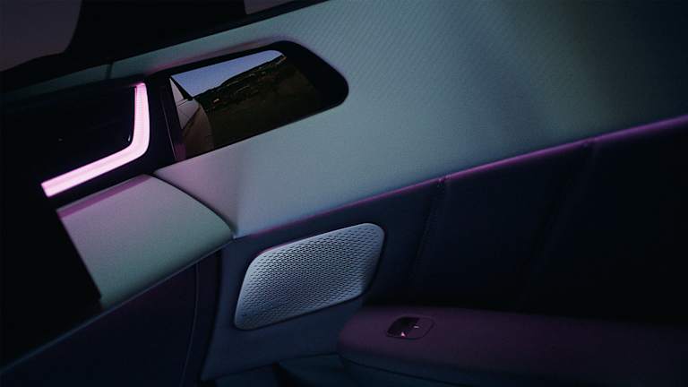 Composición de tomas interiores con el retrovisor interior digital mostrando la vista exterior, el panel trasero de climatización y un reposacabezas.