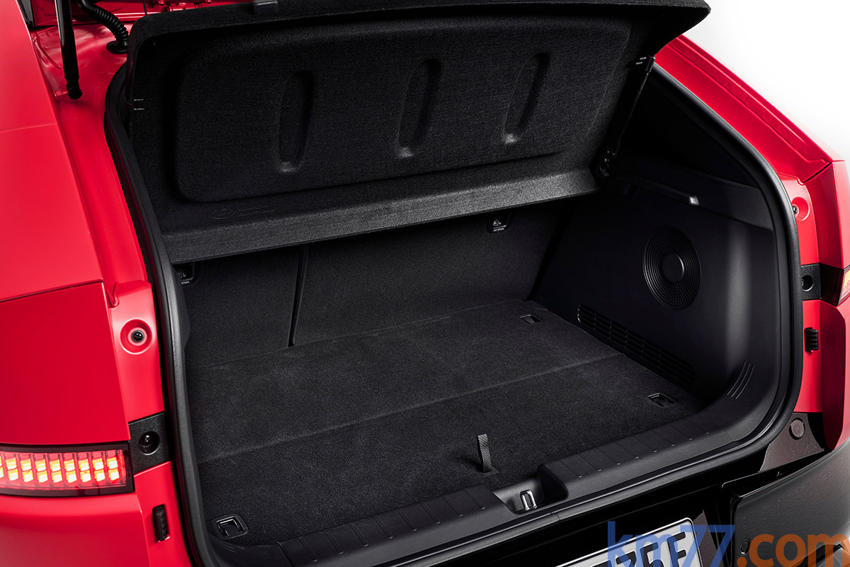 Maletero abierto de un coche rojo con alfombrilla negra y tapa de maletero