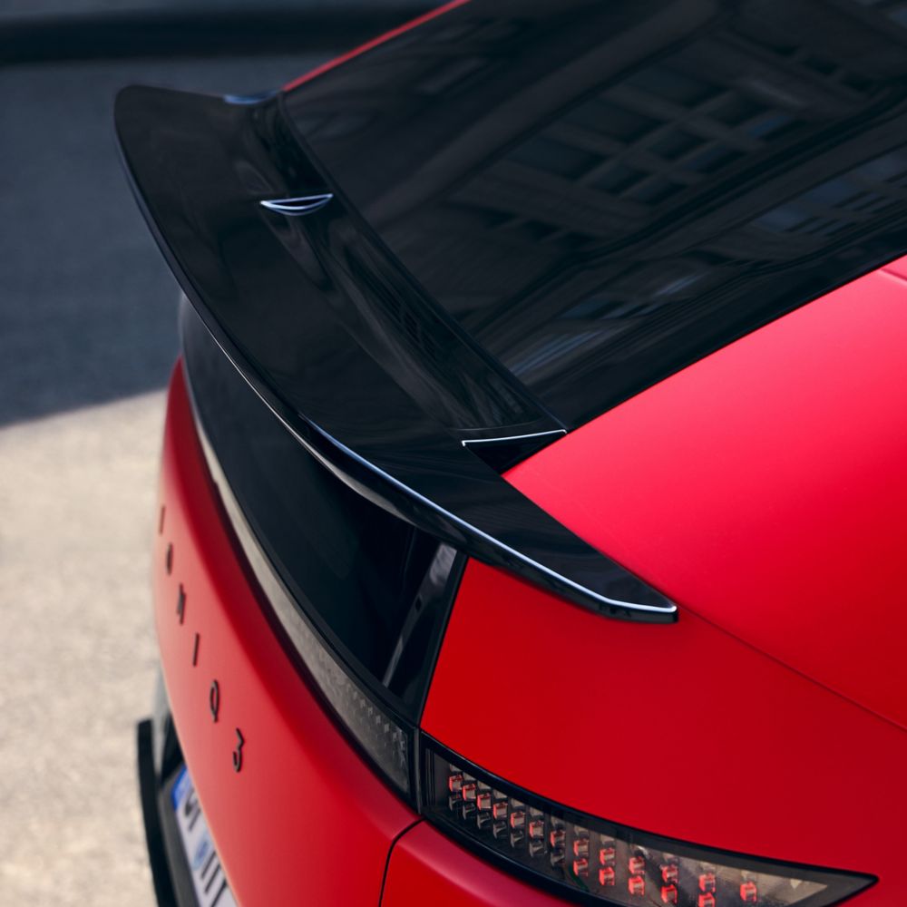 Detalle de la zaga del coche rojo con alerón negro brillante, luces traseras y la insignia IONIQ 3