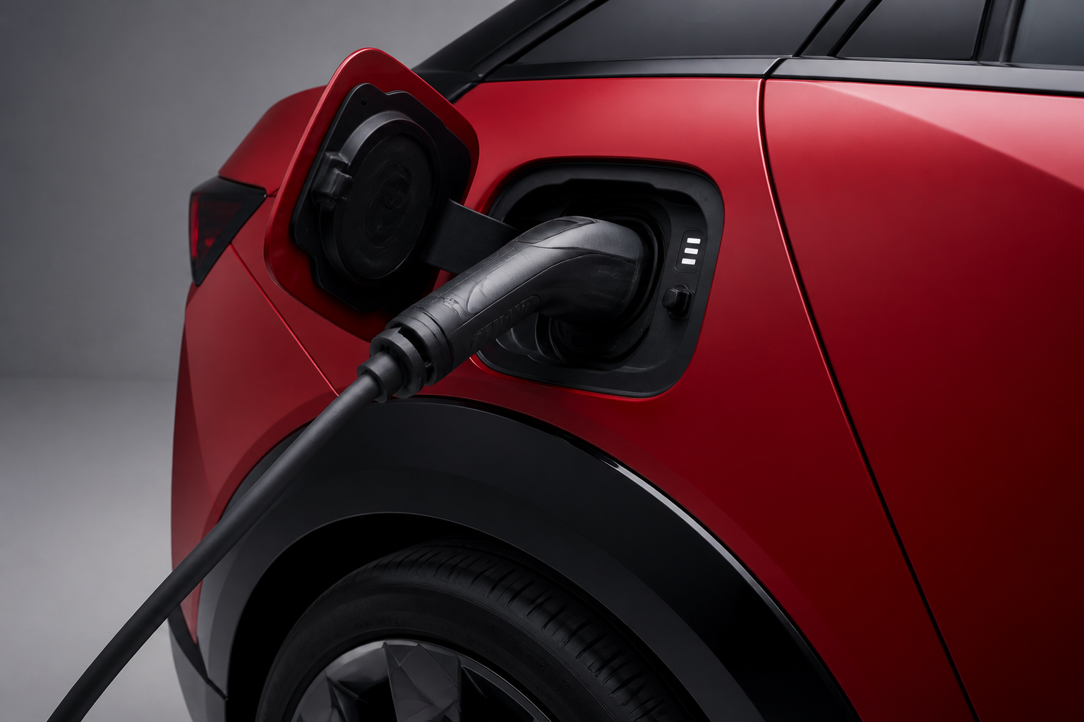 Primer plano del puerto de carga abierto del IONIQ 3 rojo con un conector de carga rápida enchufado