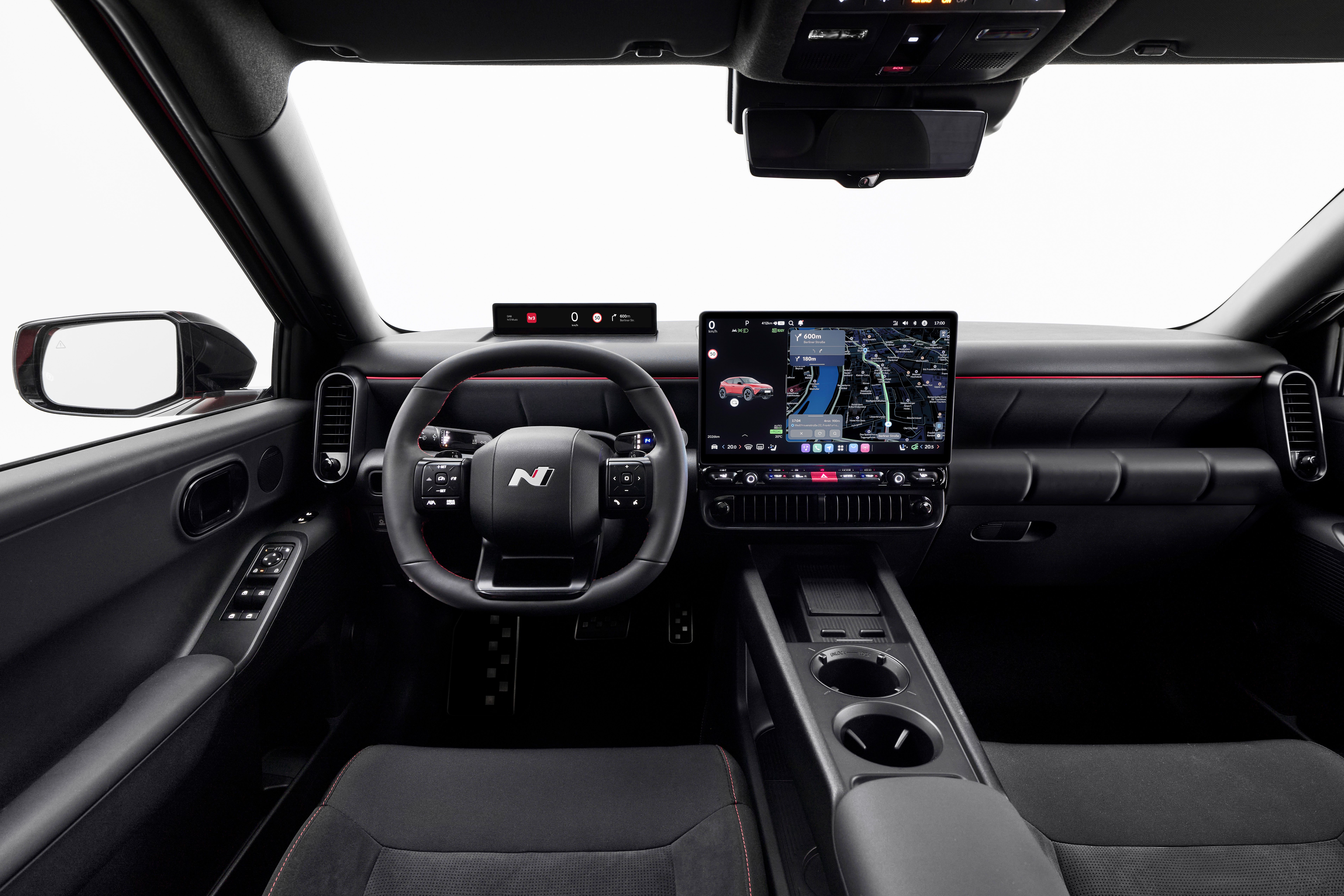 Interior con volante deportivo, cuadro de instrumentos digital, gran pantalla central de navegación y túnel central con portavasos