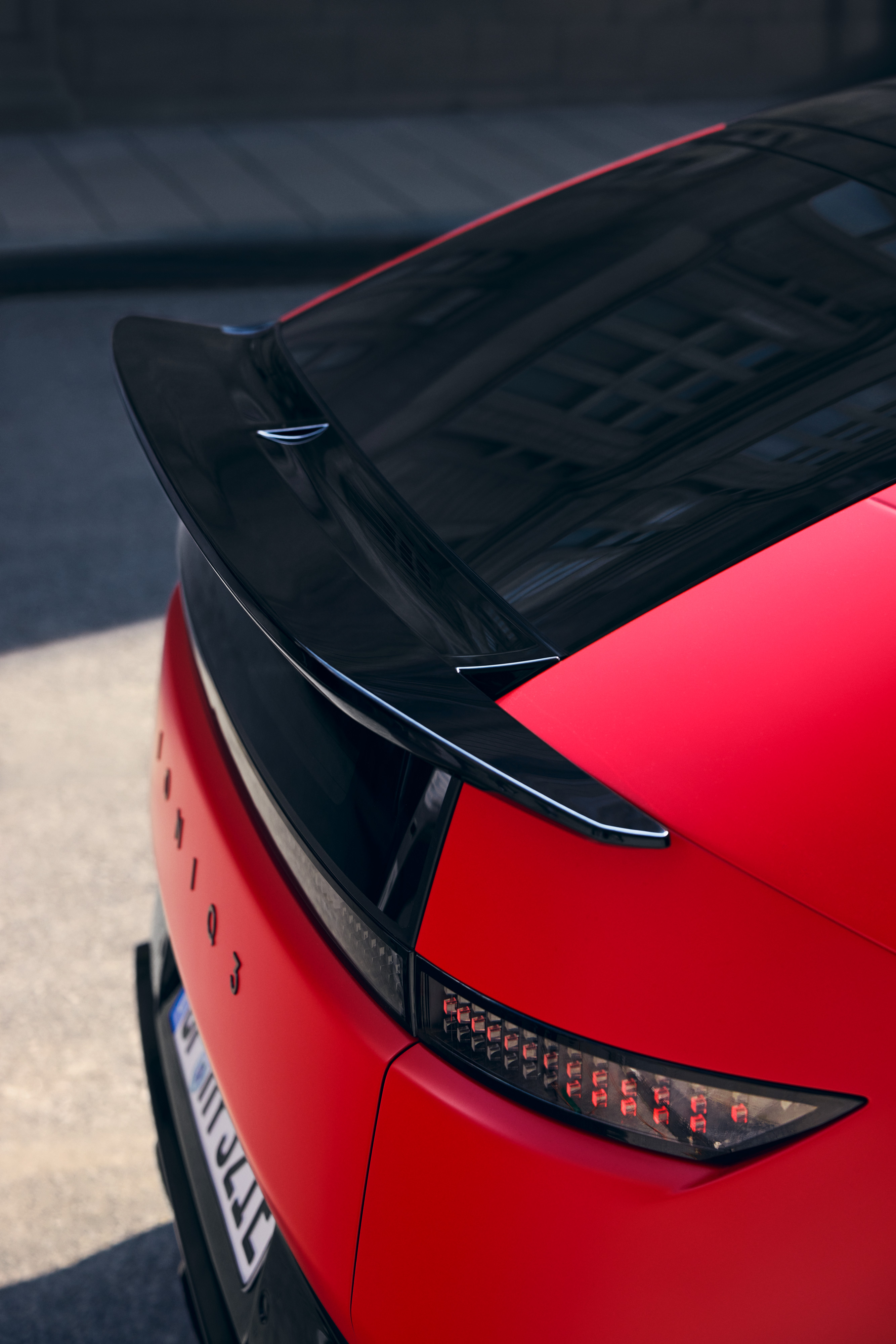 Vista trasera detallada del Hyundai IONIQ 3 en rojo mate, con faros traseros pixelados y spoiler negro