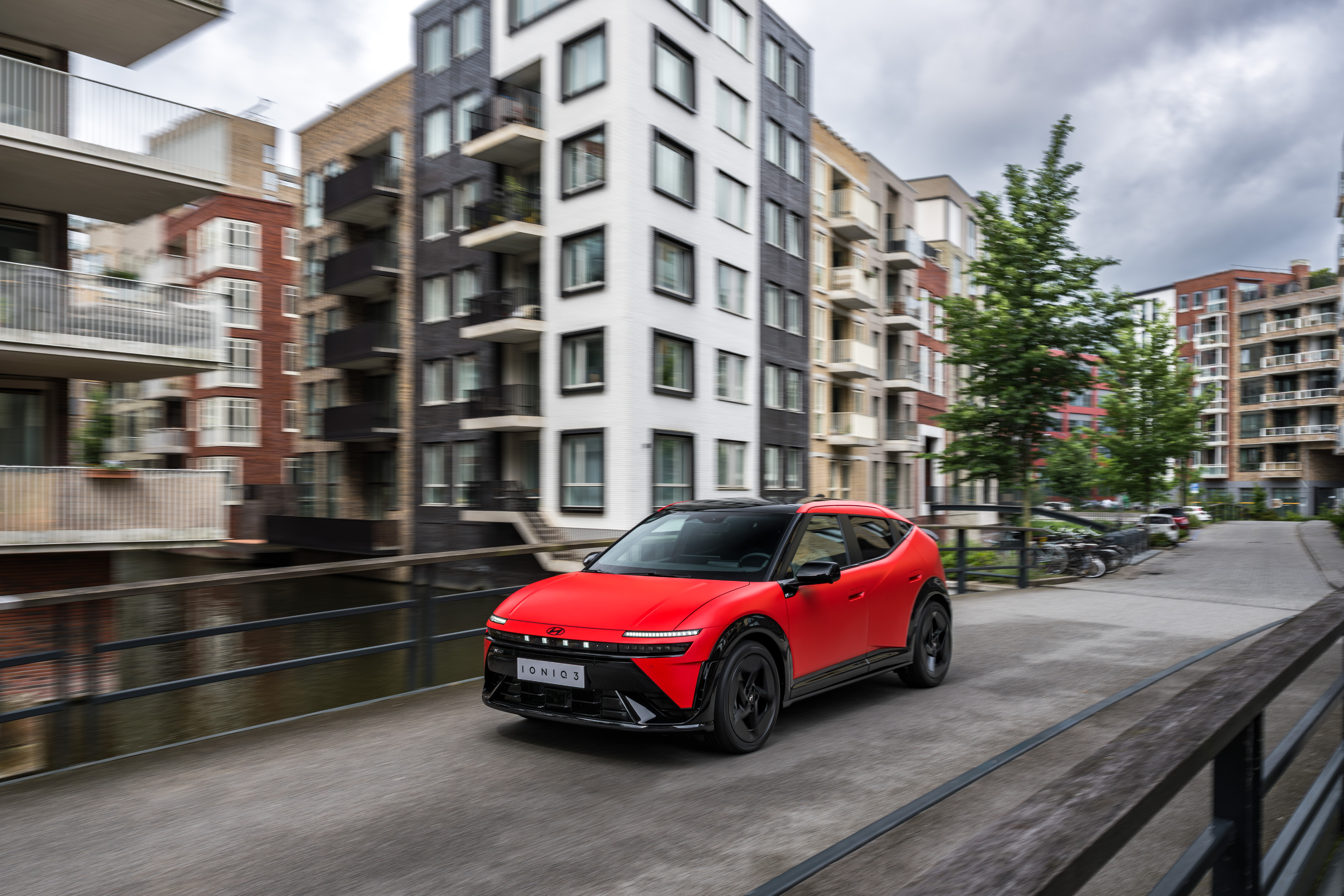 IONIQ 3 rojo parado en un paisaje verde de colinas bajo un cielo despejado