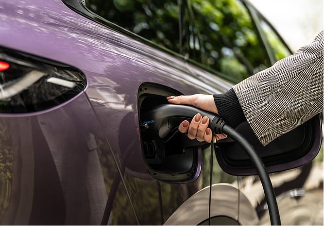 Mano conectando el cargador eléctrico al puerto de carga del vehículo