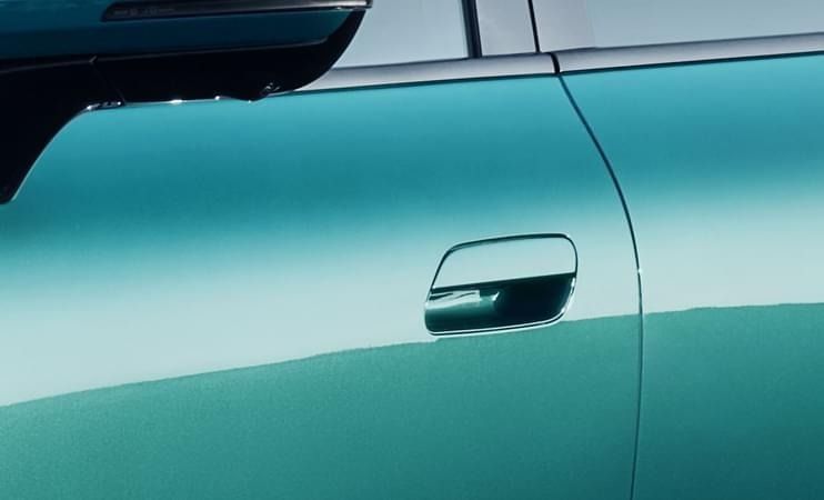 Primer plano del tirador retráctil de la puerta en la carrocería verde azulada