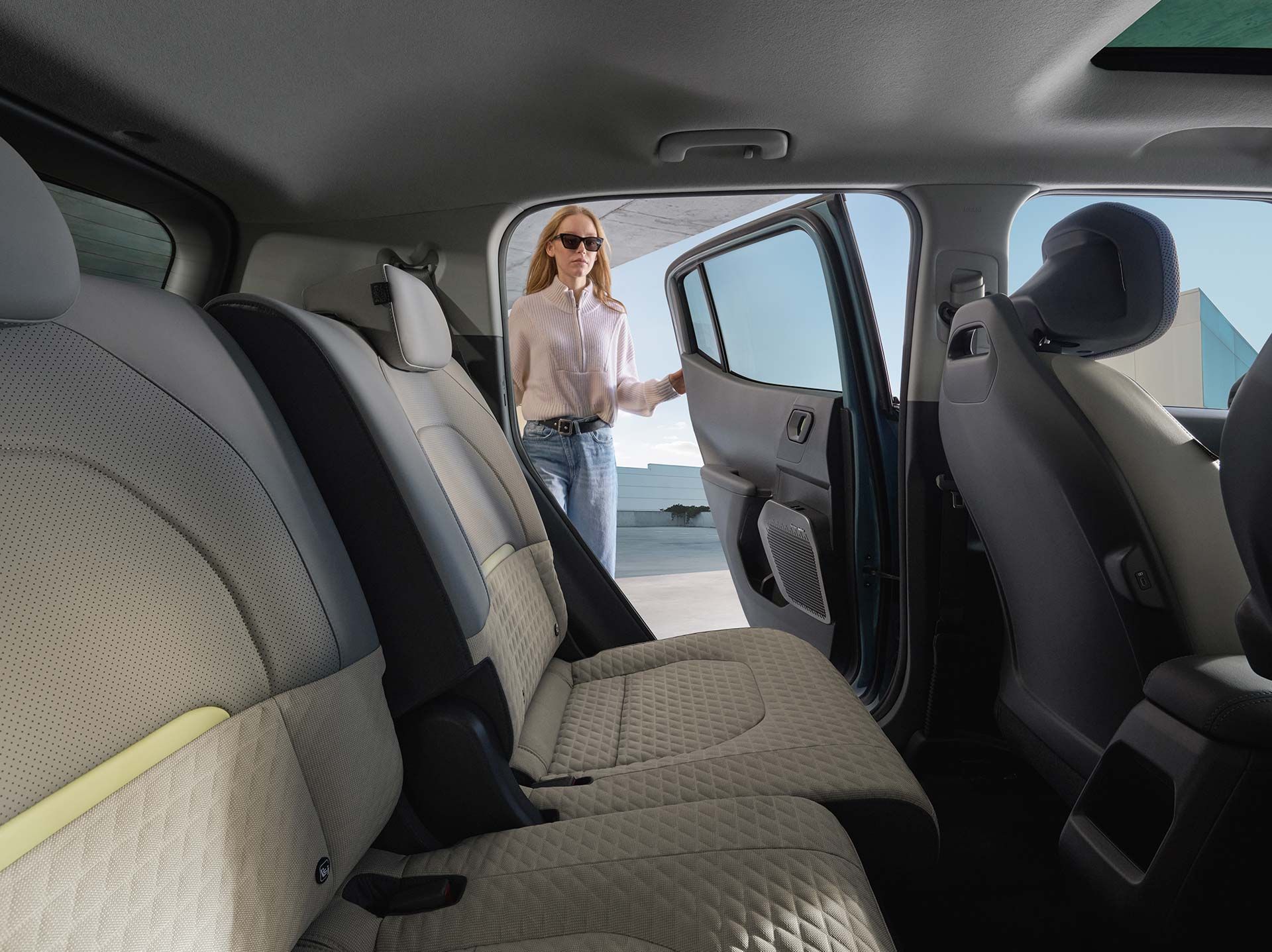 Interior del Kia EV2 visto desde las plazas traseras, con asientos claros de patrón acolchado