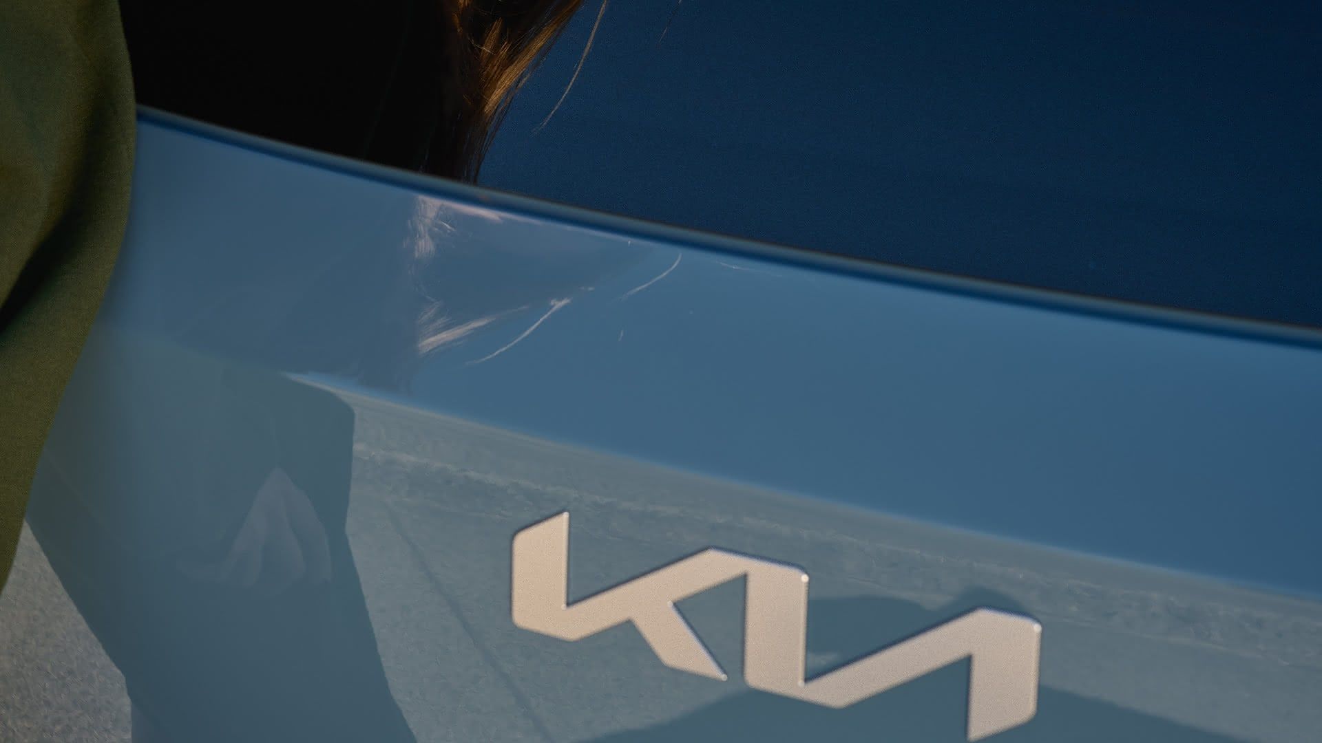 Detalle del logotipo de Kia en la parte trasera de un vehículo azul
