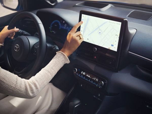 Conductor utilizando la pantalla de infoentretenimiento del Toyota Yaris con la navegación en marcha