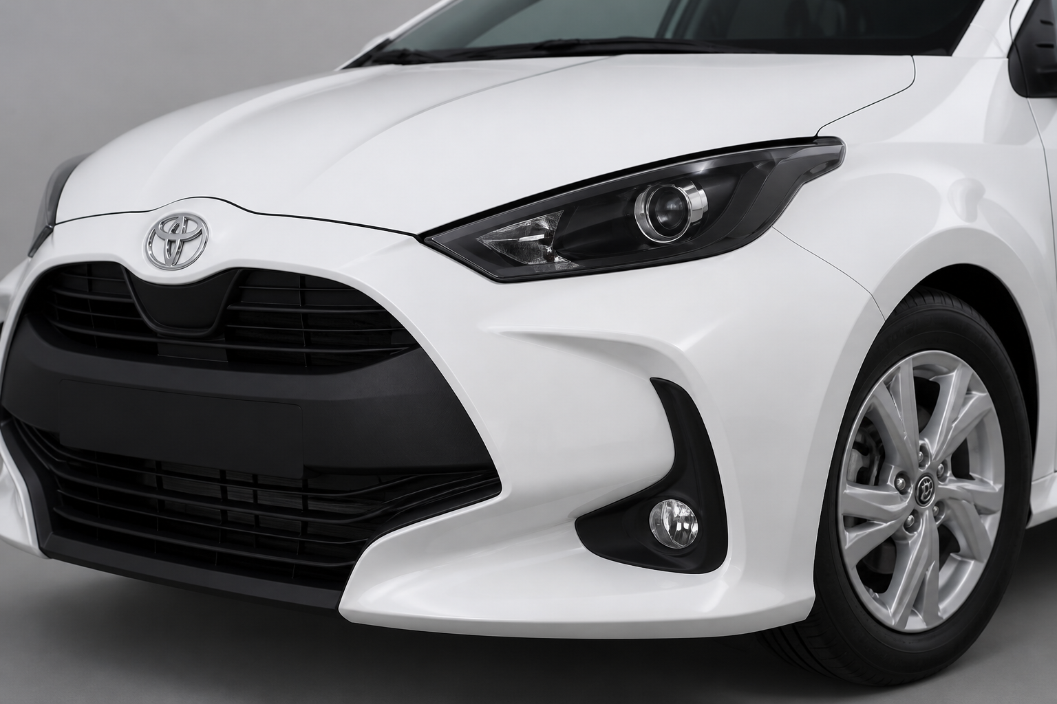 Primer plano del frontal del Toyota Yaris blanco con la parrilla y el faro delantero