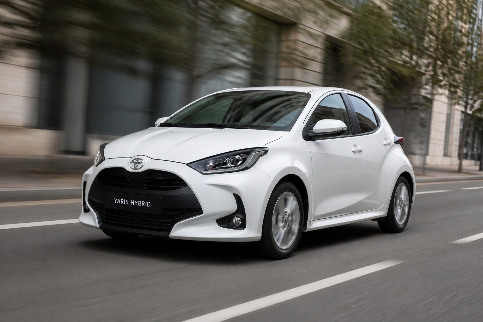 Toyota Yaris blanco en marcha por una calle urbana con el fondo ligeramente barrido por el movimiento