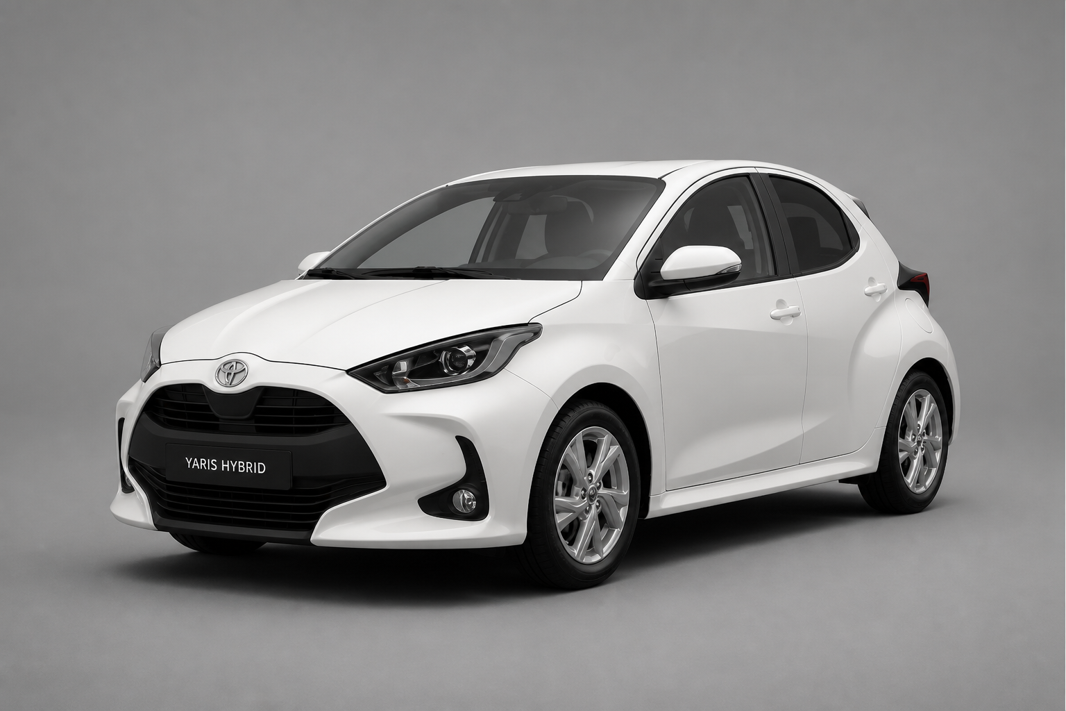 Vista tres cuartos frontal del Toyota Yaris blanco en un estudio gris neutro con iluminación suave