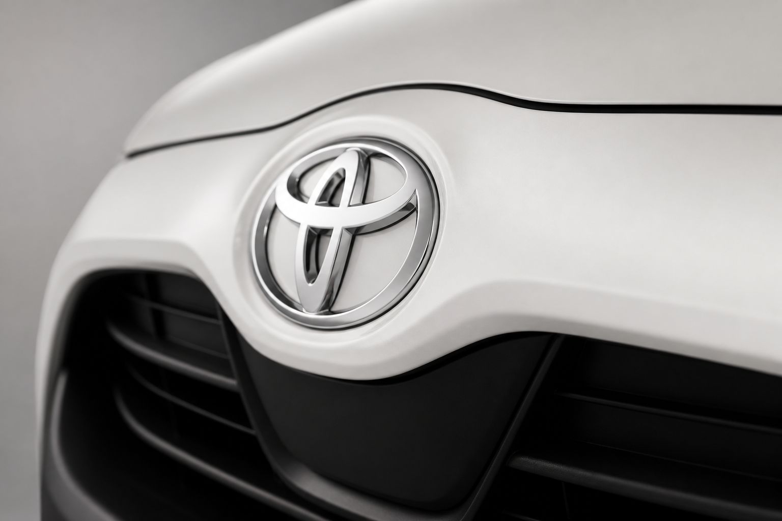 Primer plano del emblema Toyota en el frontal del coche con el fondo desenfocado