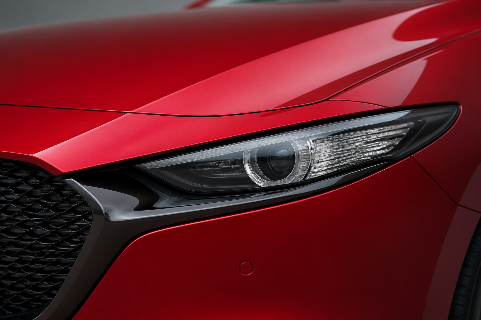 Detalle macro del faro delantero LED apagado del Mazda3 rojo, con la óptica nítida