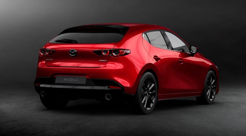 Vista trasera tres cuartos de un Mazda3 rojo oscuro con llantas negras multirradio sobre fondo oscuro