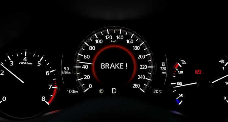 Cuadro de instrumentos con el aviso BRAKE! iluminado en rojo entre velocímetro y cuentarrevoluciones