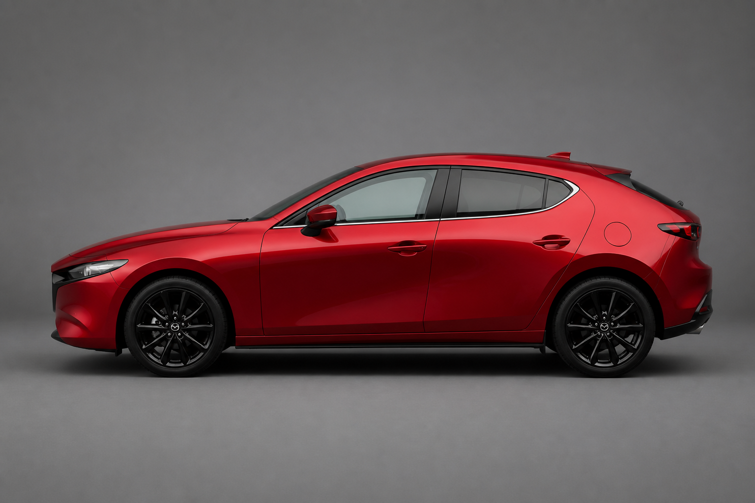 Perfil lateral puro del Mazda3 hatchback rojo en estudio neutro, con la luz recorriendo sus superficies esculpidas
