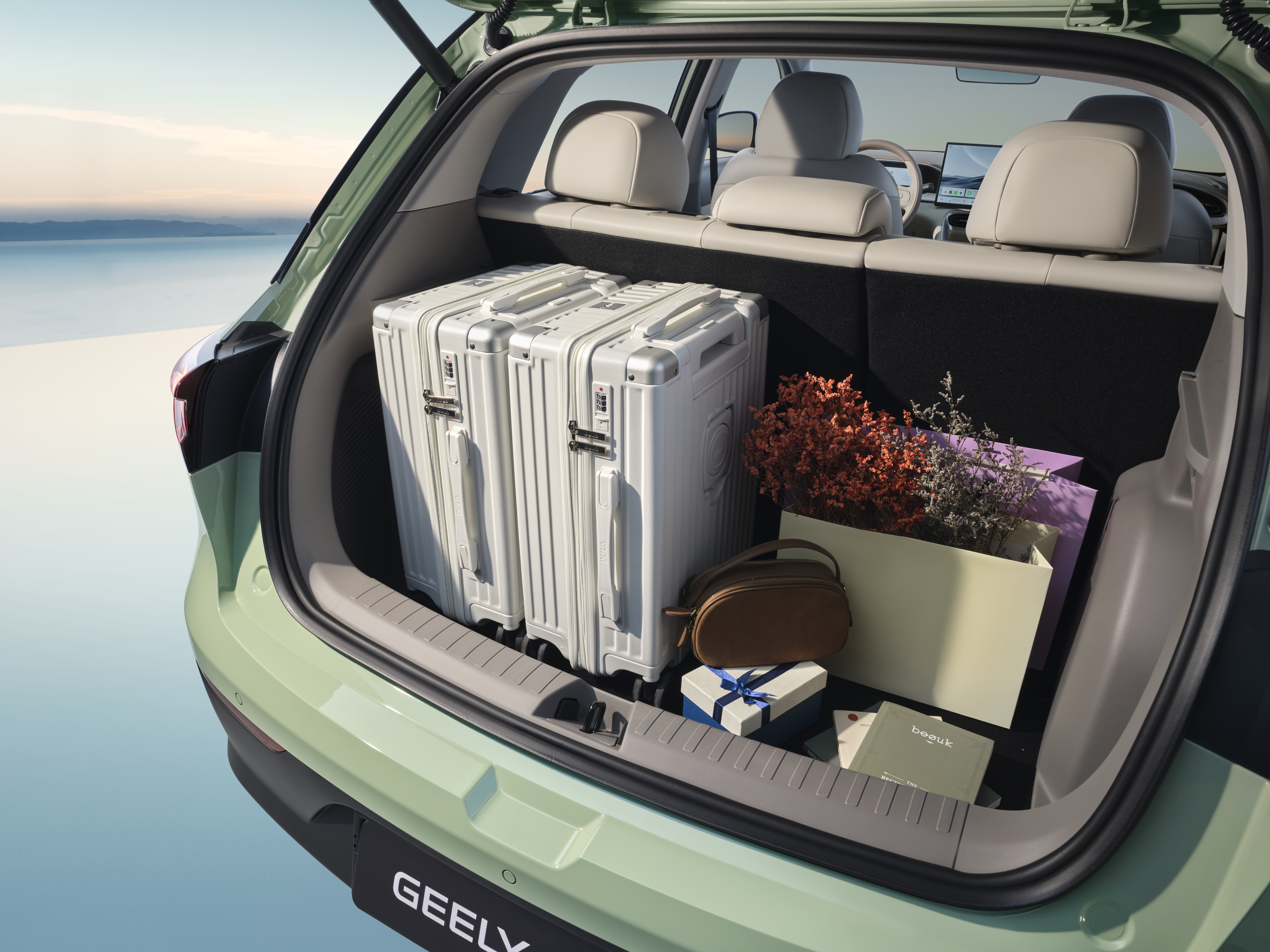 Maletero abierto de un coche verde con dos maletas blancas, un ramo de flores y un bolso, con el mar al fondo