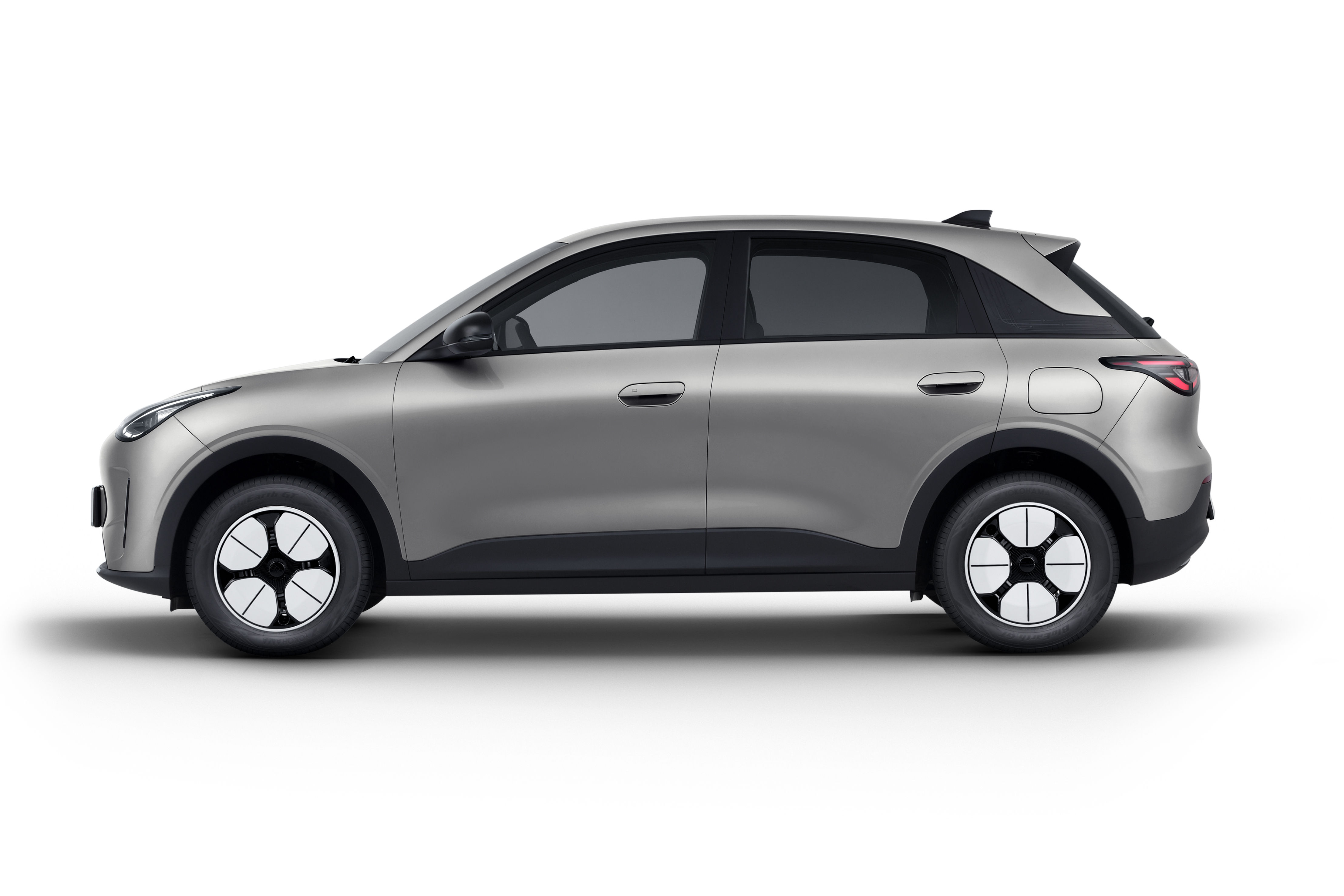 Vista lateral completa del Geely E2 en gris claro con llantas aerodinámicas bicolor sobre fondo blanco