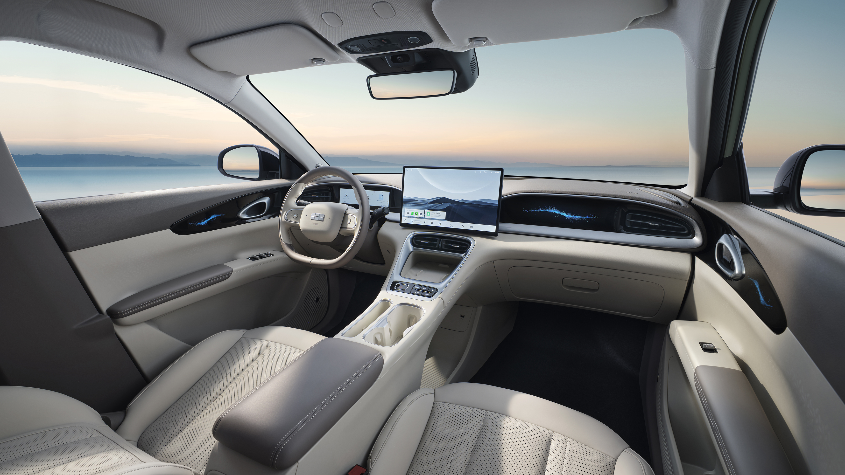 Vista panorámica del interior del coche con salpicadero, volante, pantalla central y asientos delanteros en tonos claros