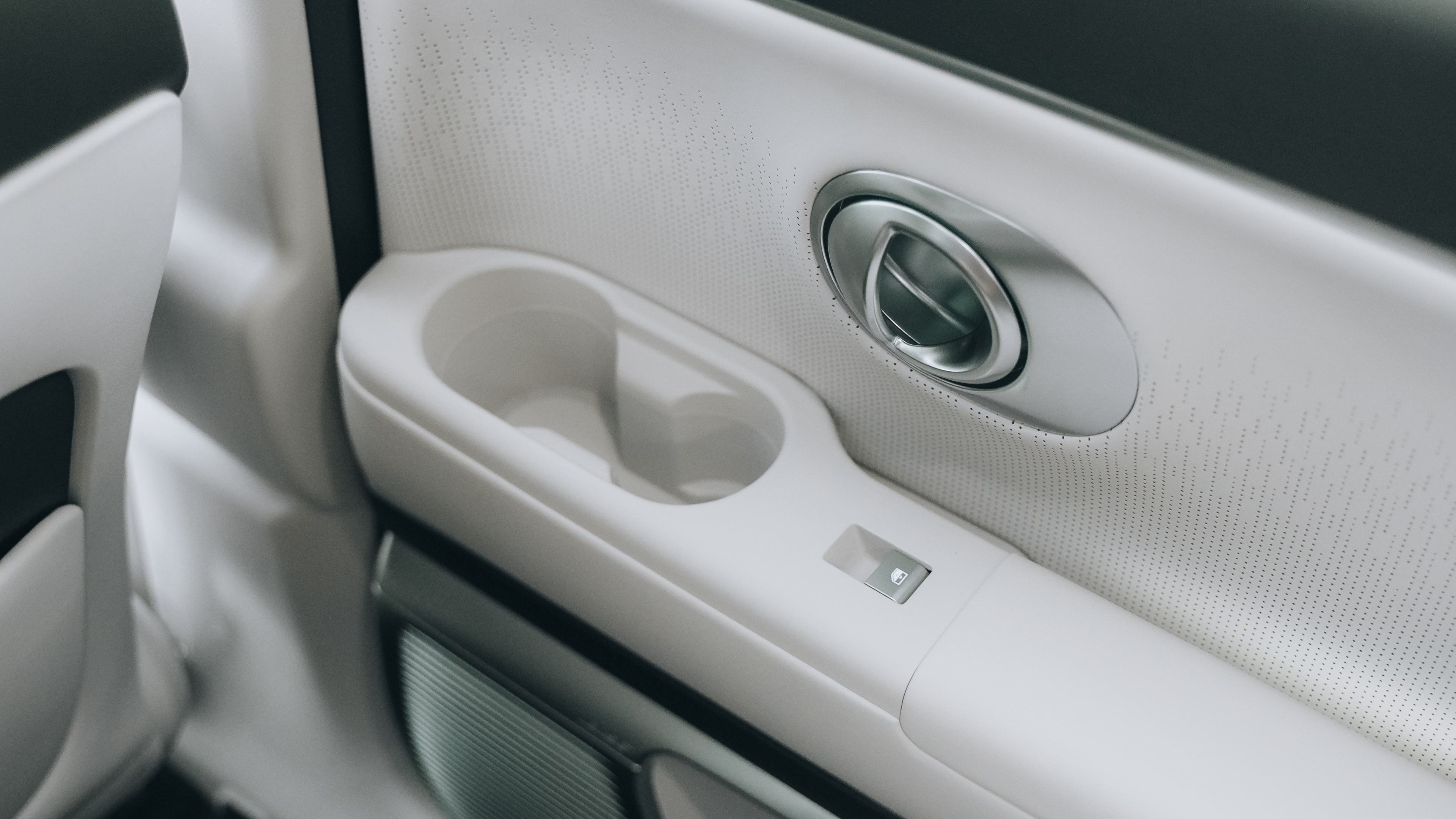 Panel de puerta interior blanco con patrón perforado, tirador metálico y portavasos