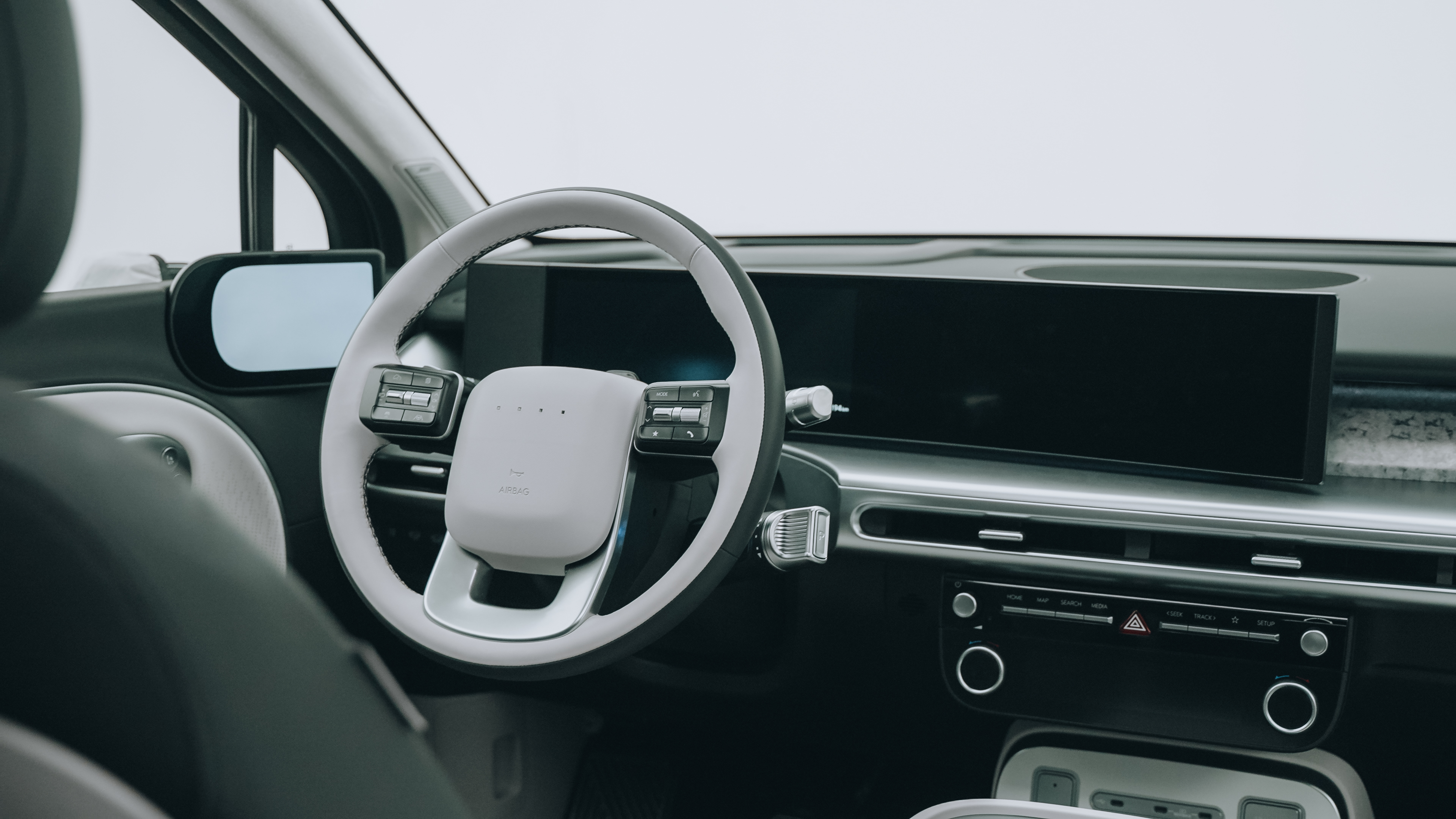Habitáculo visto desde el asiento del conductor con volante bicolor, doble pantalla y pantallas de retrovisores digitales
