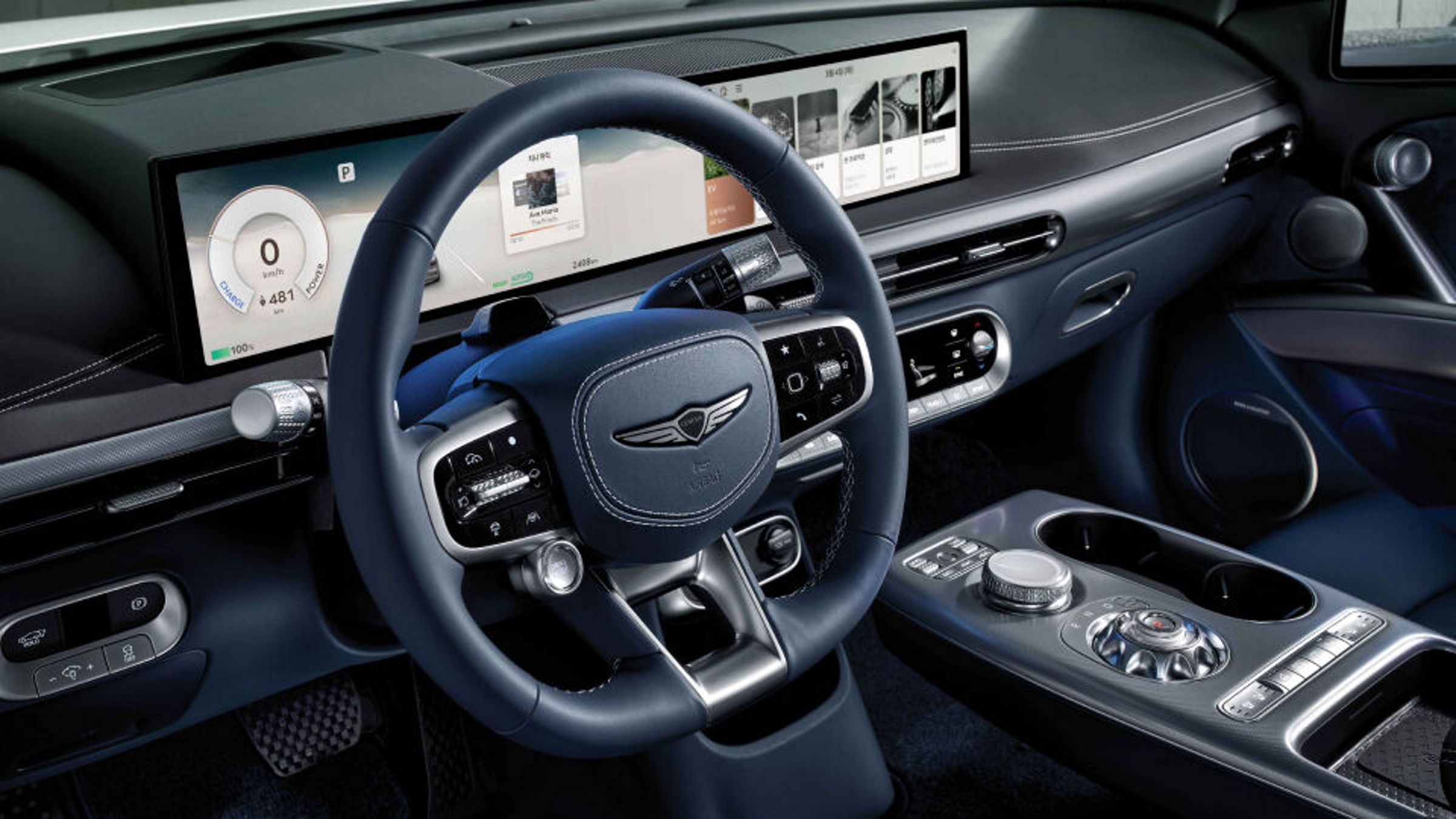 Interior del GV60 con volante, salpicadero, pantalla de infoentretenimiento y retrovisores laterales digitales en tonos azules