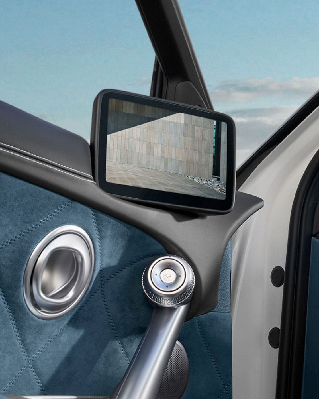 Panel de puerta del GV60 con tapicería acolchada azul, tirador metálico y pantalla del retrovisor digital
