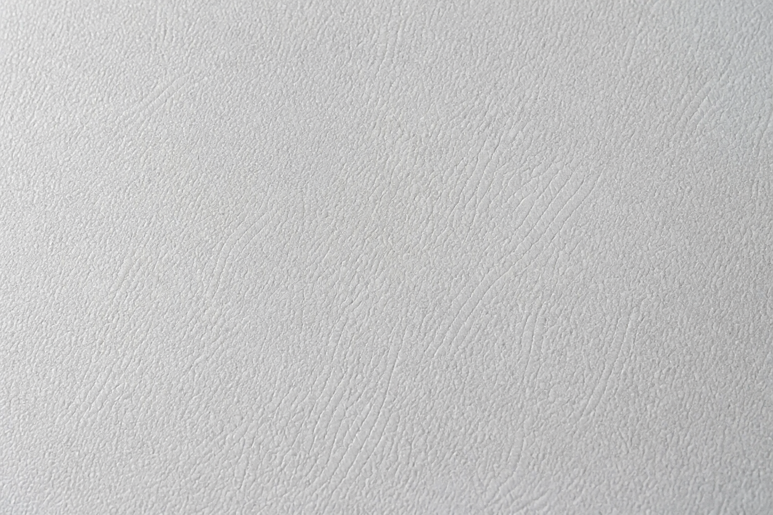 Macro de la textura de un tapizado vinílico técnico de superficie mate, con luz lateral suave.
