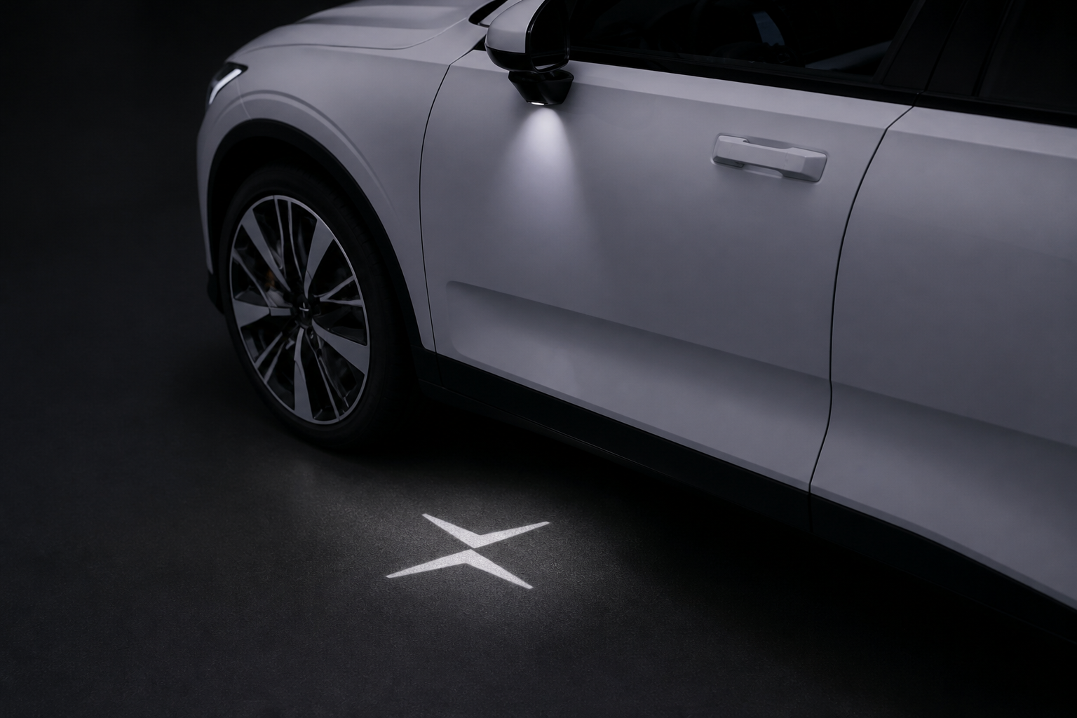 Detalle nocturno de la proyección del logotipo Polestar en el suelo bajo la puerta de un coche blanco aparcado.