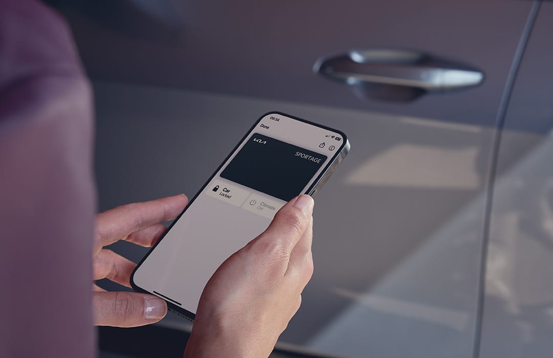 Mano sosteniendo un smartphone con la aplicación Kia Connect abierta mostrando el Sportage