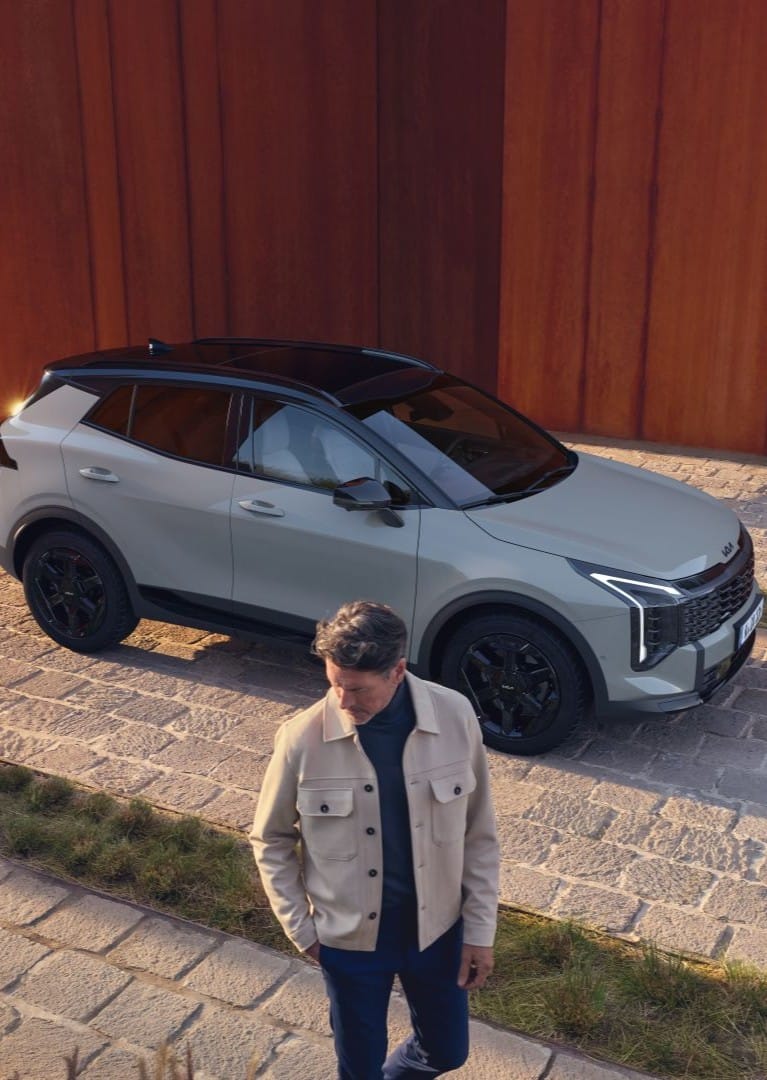 Vista aérea del Kia Sportage gris con techo negro aparcado sobre adoquines