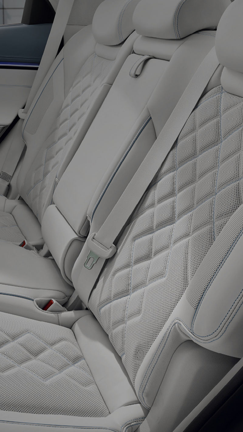 Asientos traseros tapizados en piel blanca con patrón de diamante perforado y costuras azules.