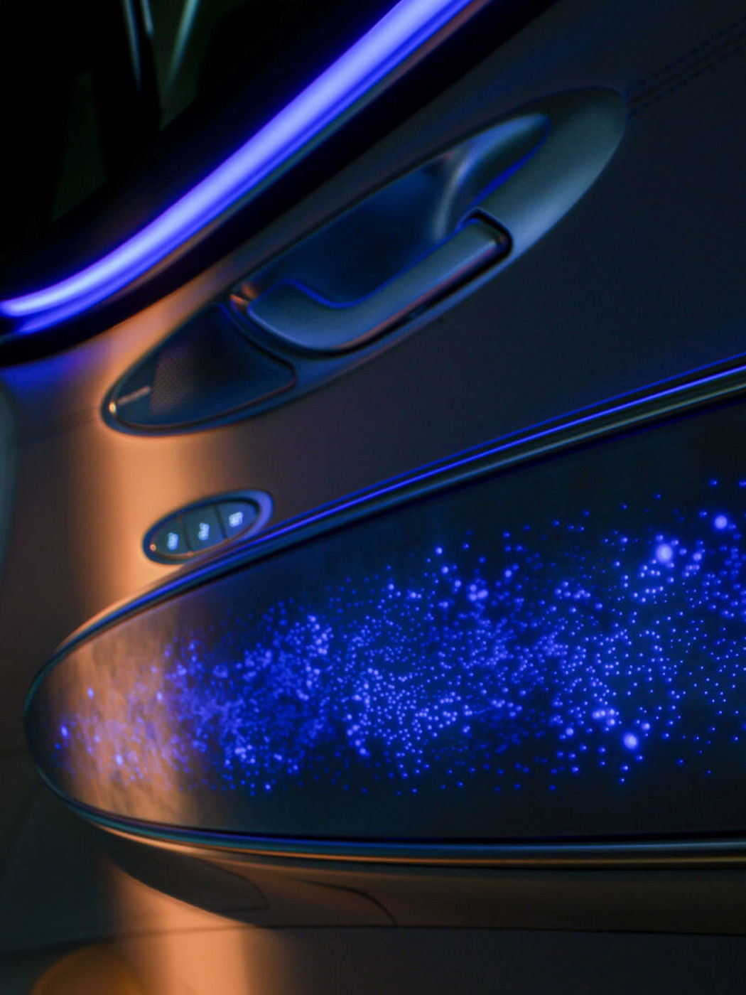 Panel de puerta interior con altavoz Bang & Olufsen y tira de iluminación ambiental con efecto de constelación en tonos azules y púrpura.