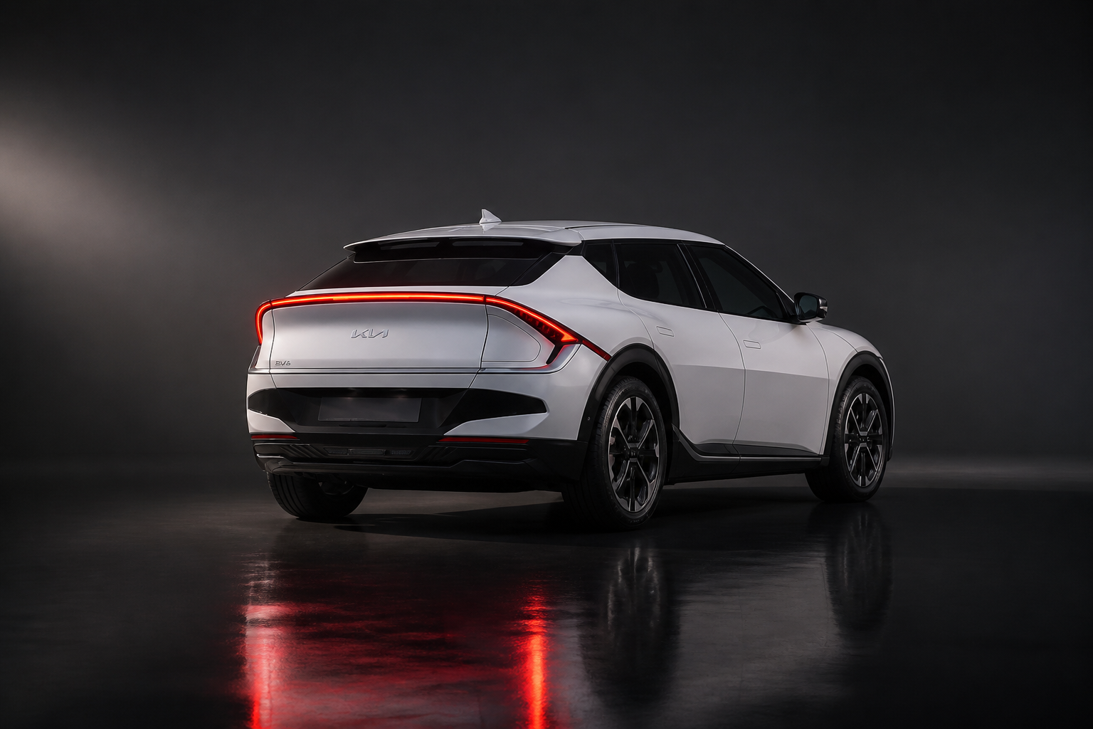 Kia EV6 blanco en un plató de luz dramática, vista trasera tres cuartos con la firma lumínica reflejada en el suelo