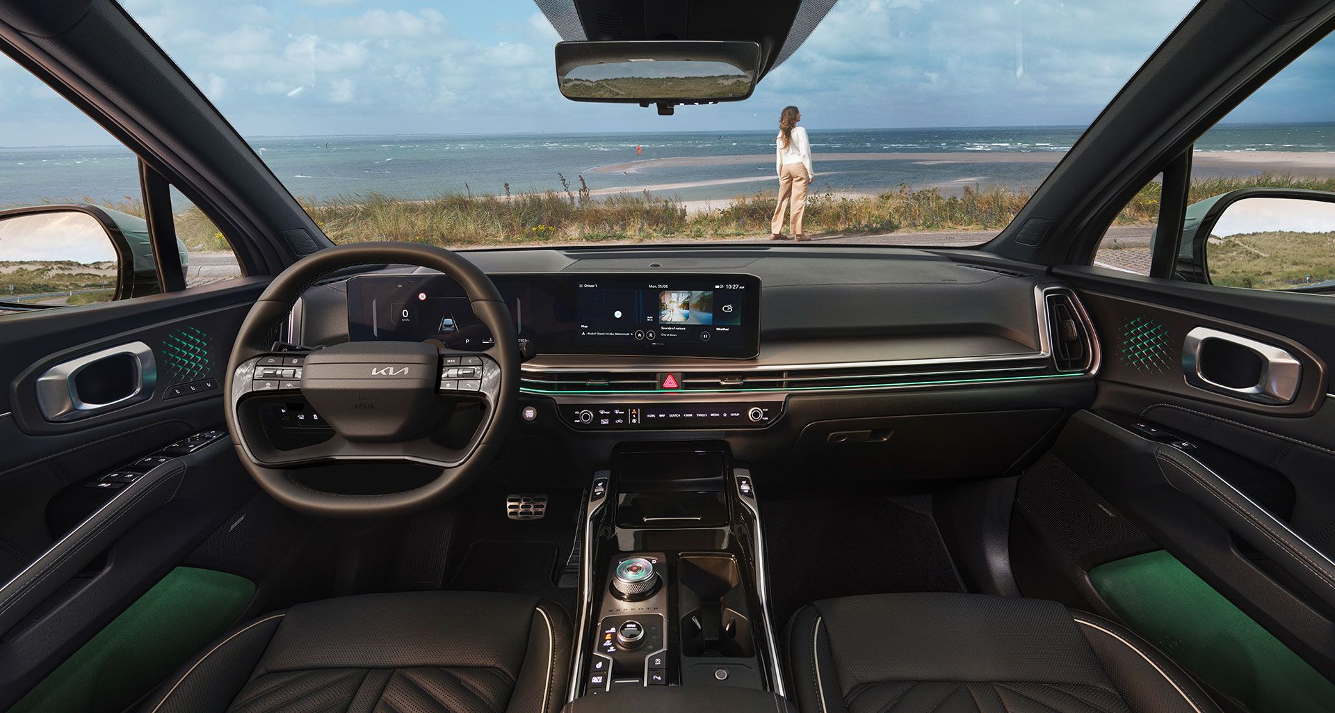 Interior oscuro del Kia Sorento con una persona recostada en el asiento del copiloto, vista desde el lado del conductor, con la consola central y la pantalla parcialmente visibles