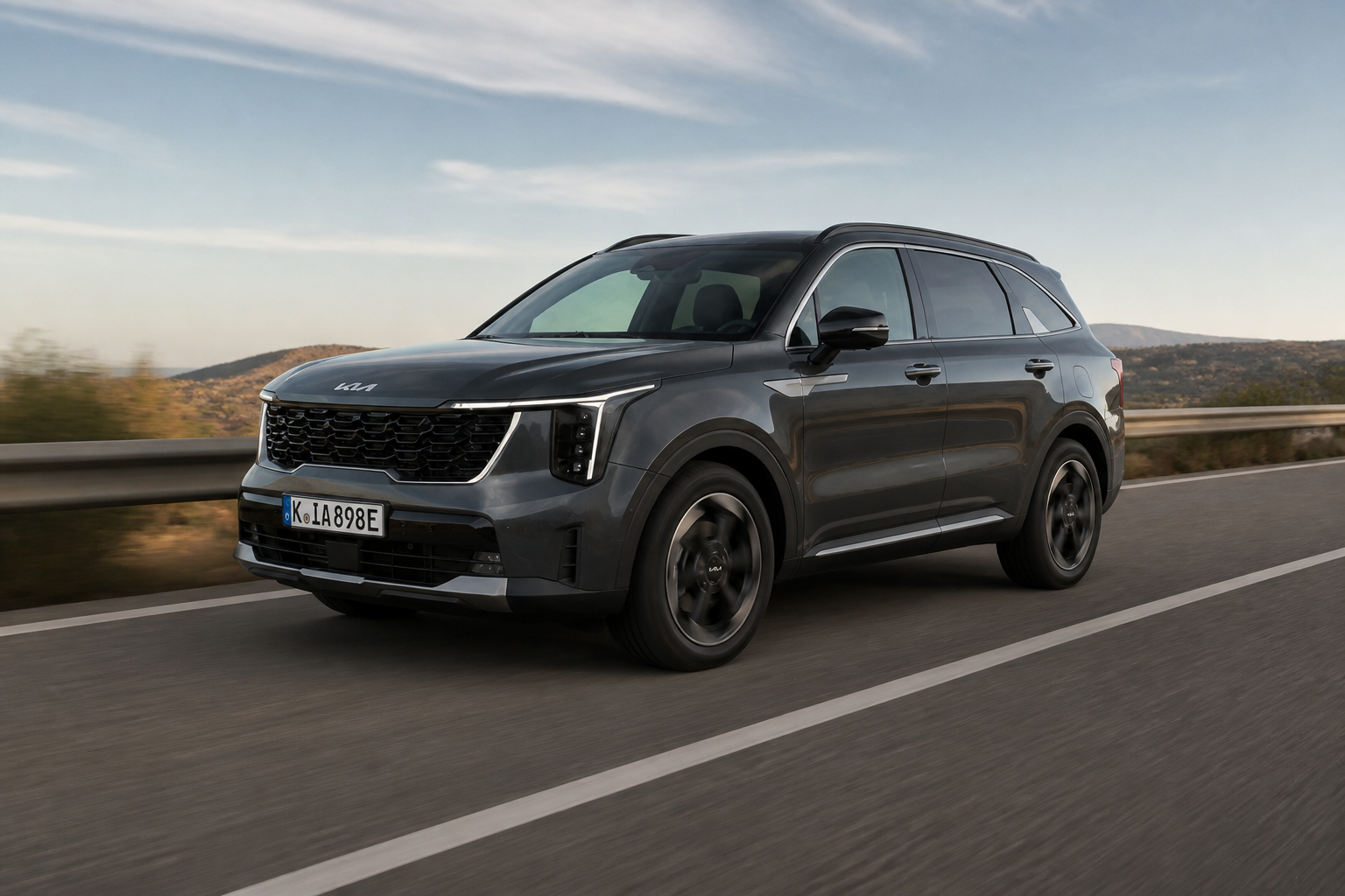 Kia Sorento gris circulando por una carretera abierta con luz de tarde