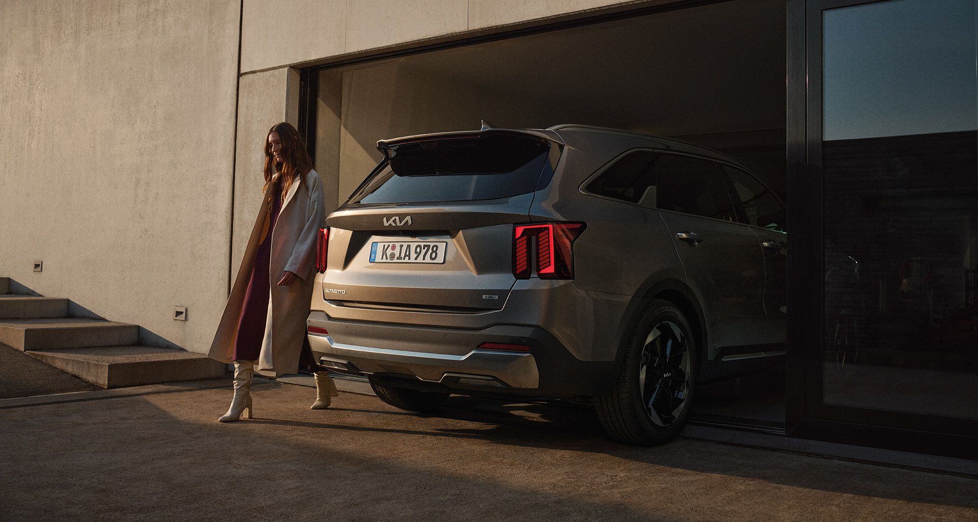 Trasera de un Kia Sorento gris oscuro saliendo de un garaje con los pilotos traseros visibles