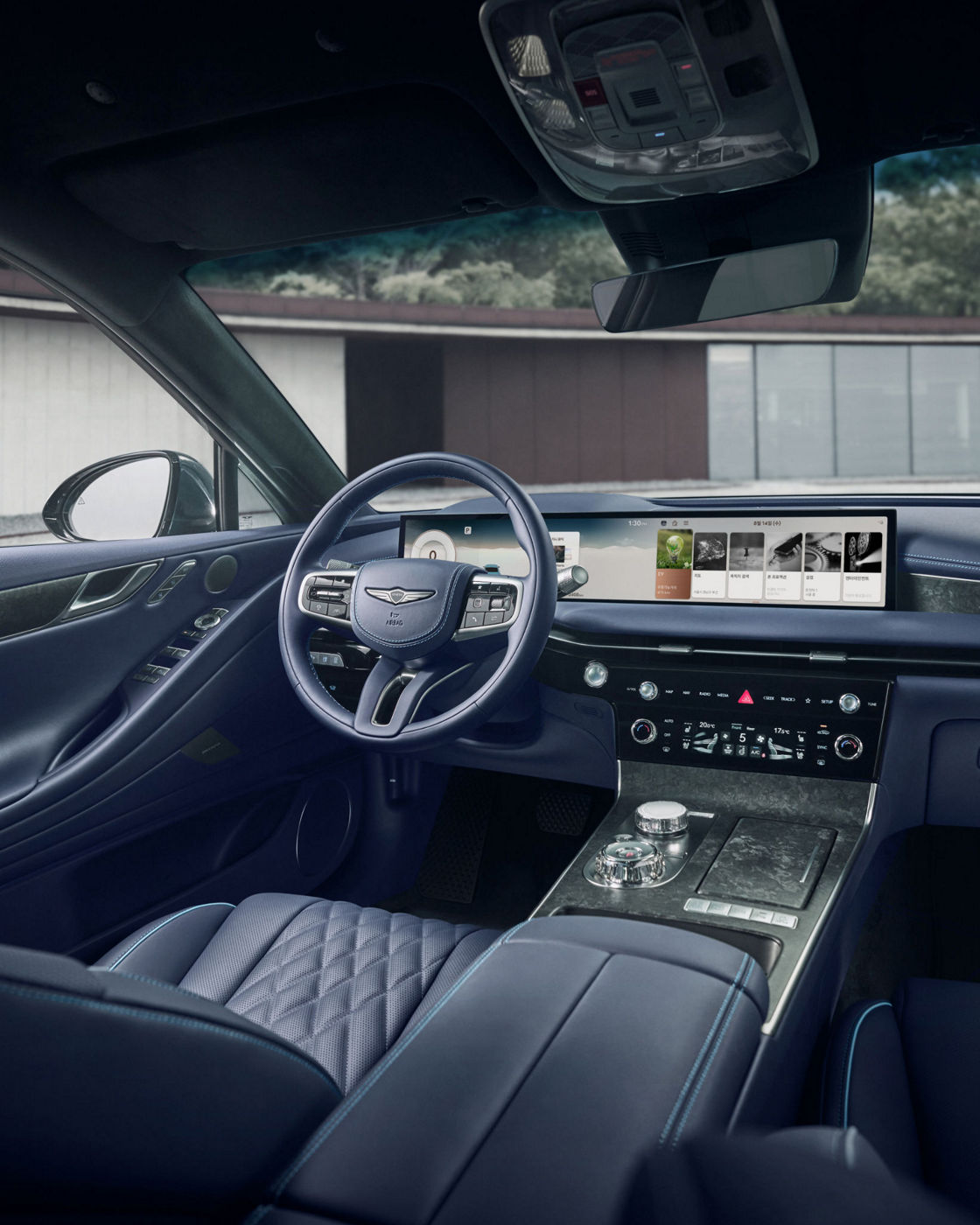 Interior del Electrified G80 en azul oscuro con salpicadero, volante y pantalla de infoentretenimiento